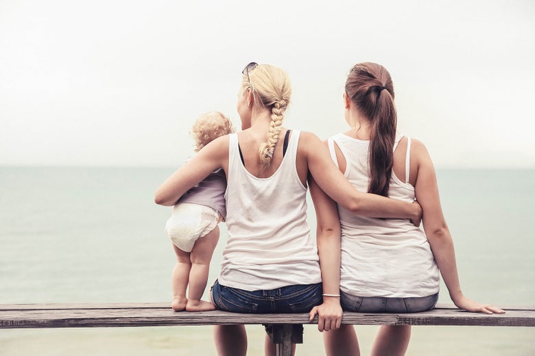 A lesbian couple with their baby at the beach.